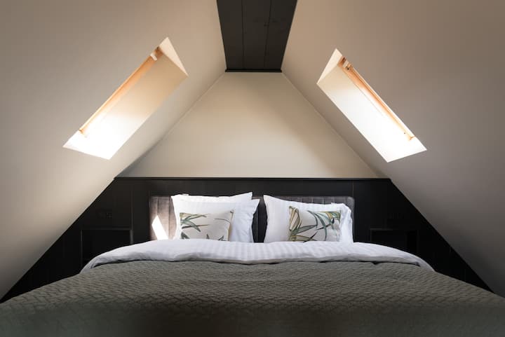 Slaapkamer boven met queensize bed en 2 ramen 