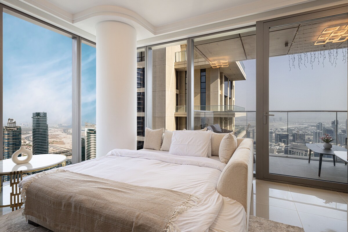Een luxe slaapkamer met kamerhoge ramen biedt een adembenemend panoramisch uitzicht op de stad.