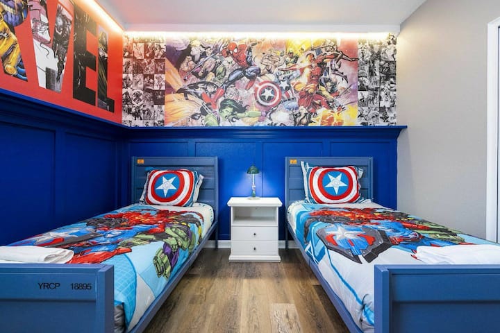 חדר הילדים התוסס הזה כולל קירות כחולים בהירים ושתי מיטות יחיד עם מצעים צבעוניים של גיבורי על מנת ליצור אווירה מרגשת למשחקים יצירתיים ולילות שלוים, המשופרים על ידי ציור קיר נועז ועיצוב שובב.