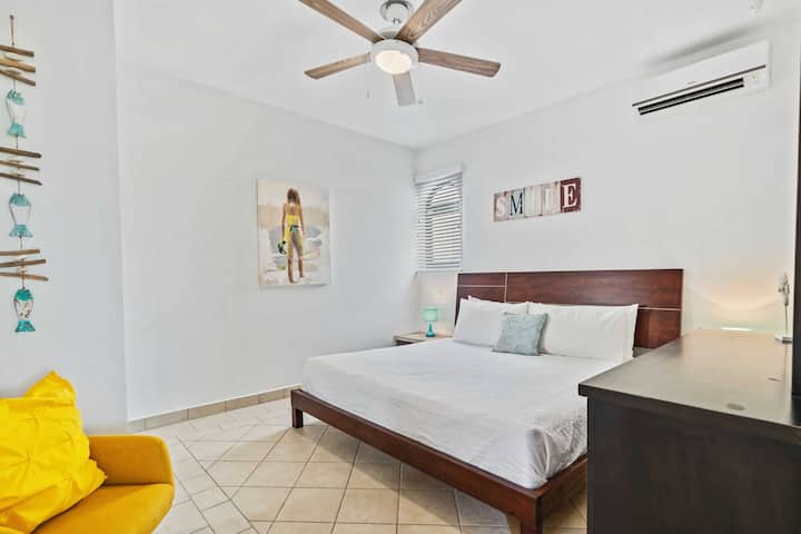 -卧室配有加大双人床和现代木质床头板
-明亮的黄色装饰椅子和海滩主题的墙壁艺术增添了个性和色彩
-自然光透过窗户充满房间，增进通风的氛围