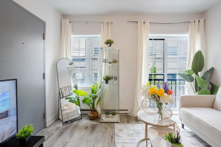 Bright living room with layered greenery, sheer curtains, and curated modern decor for a relaxed stay