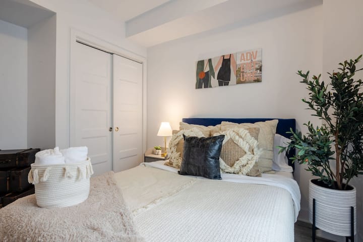 Bedroom 1: Serene bedroom with soft textures, leafy accents, and cozy bedside lighting