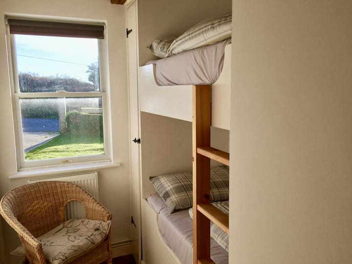 ห้องนอนแบบสองชั้นพร้อมชุดเตียงสองชั้น เก้าอี้นวม และวิวสวน