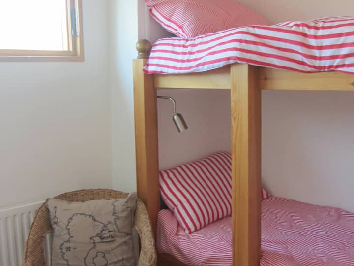 ห้องนอนพร้อมเตียงสองชั้นเก้าอี้ตะกร้าและหน้าต่าง