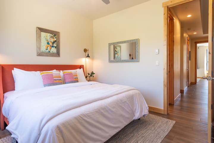 - Wake up refreshed in this inviting bedroom with soft white bedding, accent pillows, and colorful touches
- Natural light and a hallway view create an airy, welcoming atmosphere
- Peaceful place to start and end your mountain adventure days