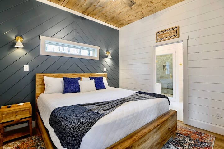 סוויטת Master King, למטה, מציעה מיטת קינג סייז עם מצעים שופעים ומוקפת באורות פמוט לקריאה.