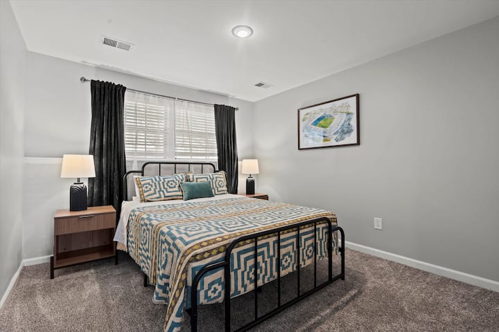 חדר שינה בקומה התחתונה עם מיטת קווין סייז, תאורה רכה ועיצוב נעים לשהייה שקטה ורגועה.