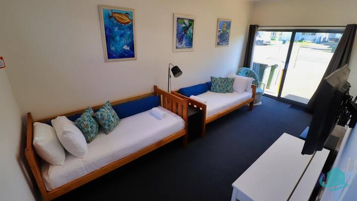 Tercer dormitorio con dos camas individuales y TV montada en la pared