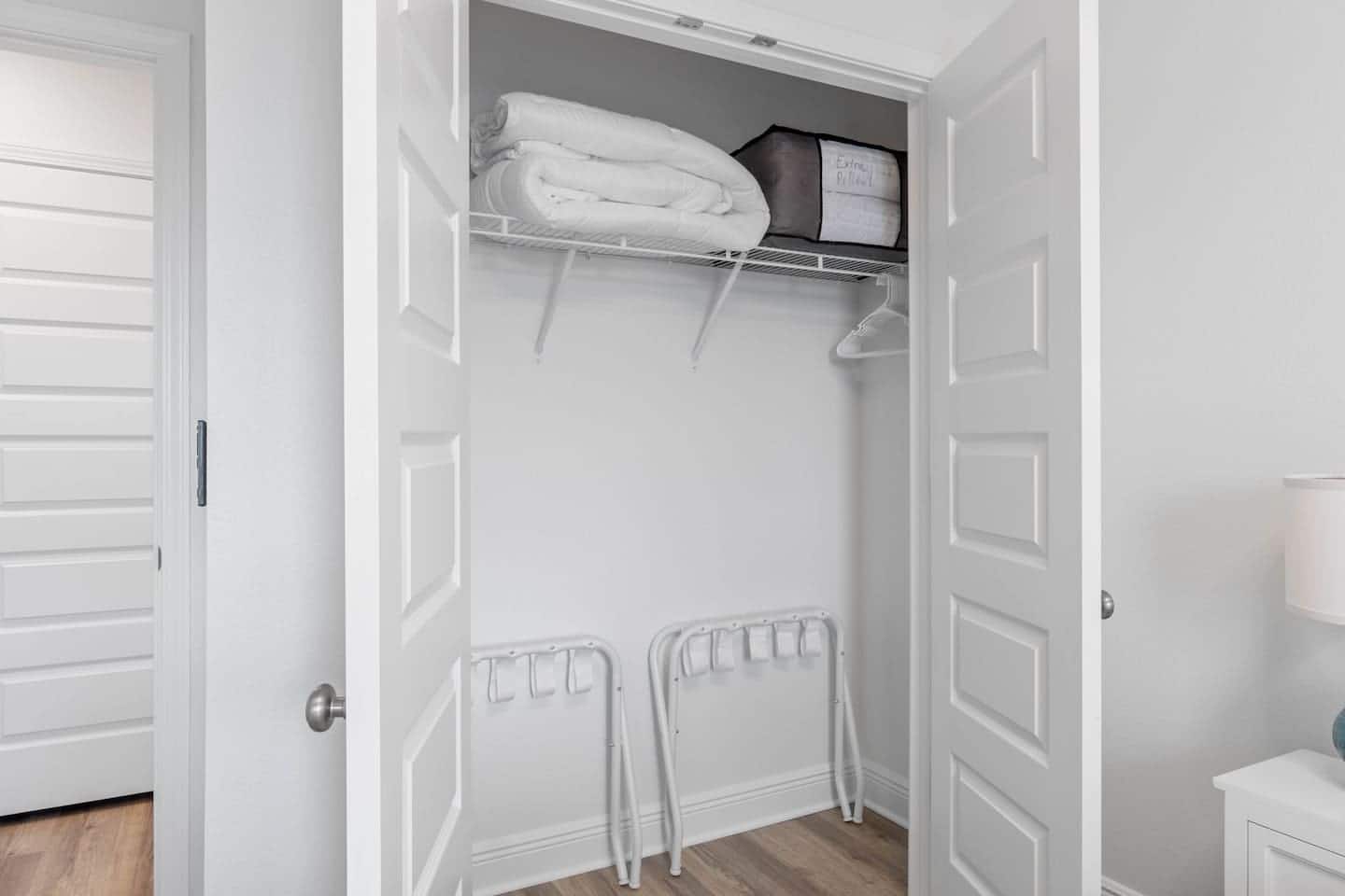 Double closet with hangers, extra blanket, pillows, and suitcase racks