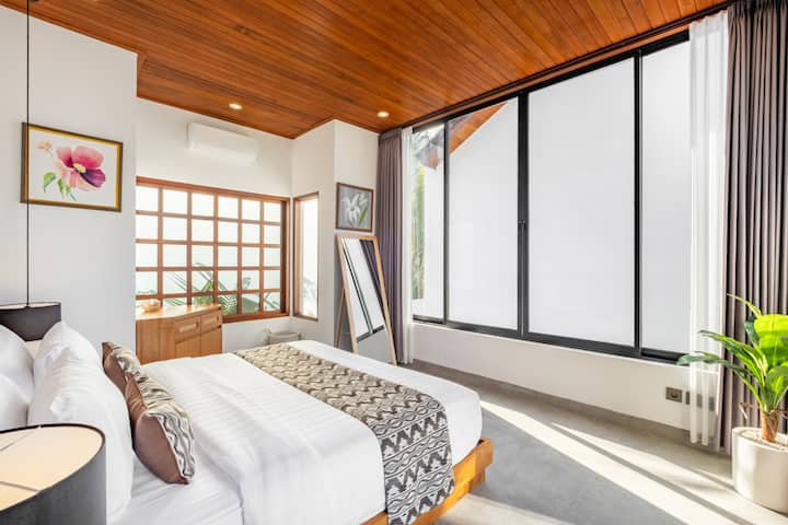 Udobna moderna spavaća soba s drvenim detaljima, blagim osvjetljenjem i minimalističkim uređenjem.