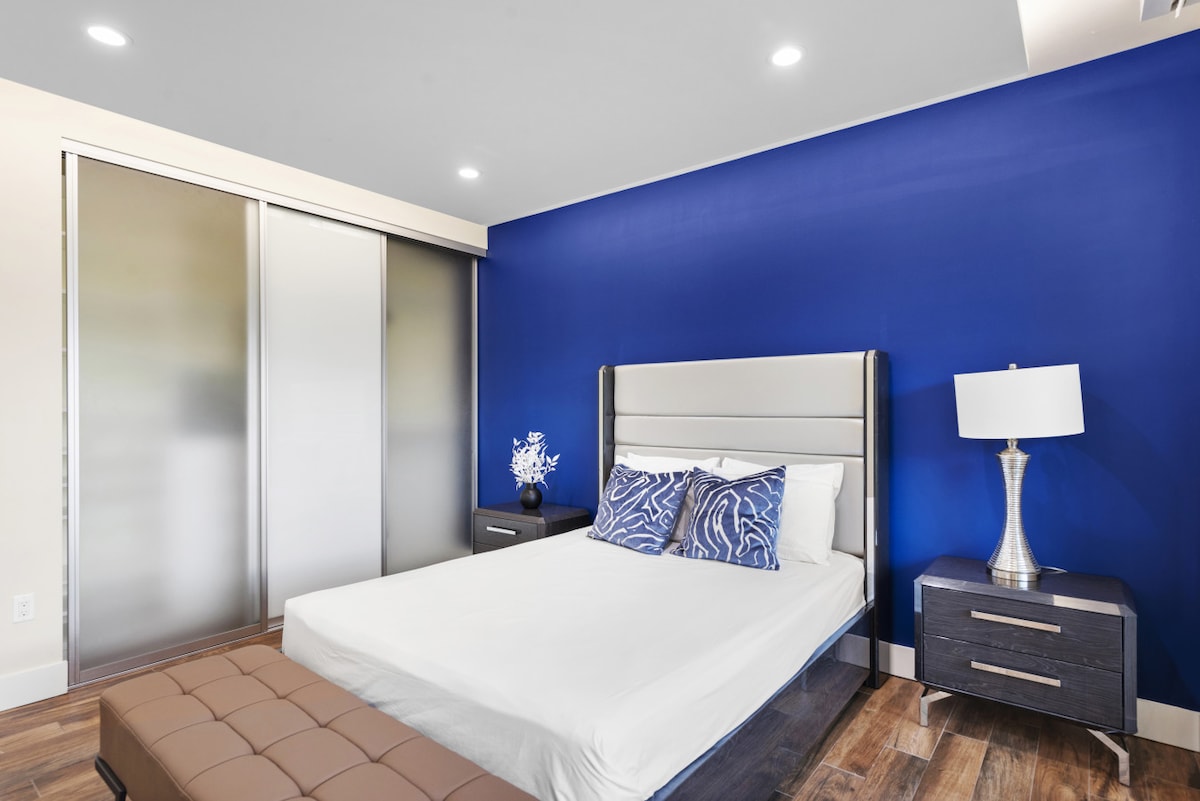 Dormitorio elegante con una pared azul llamativa, puertas de armario esmeriladas y una decoración moderna