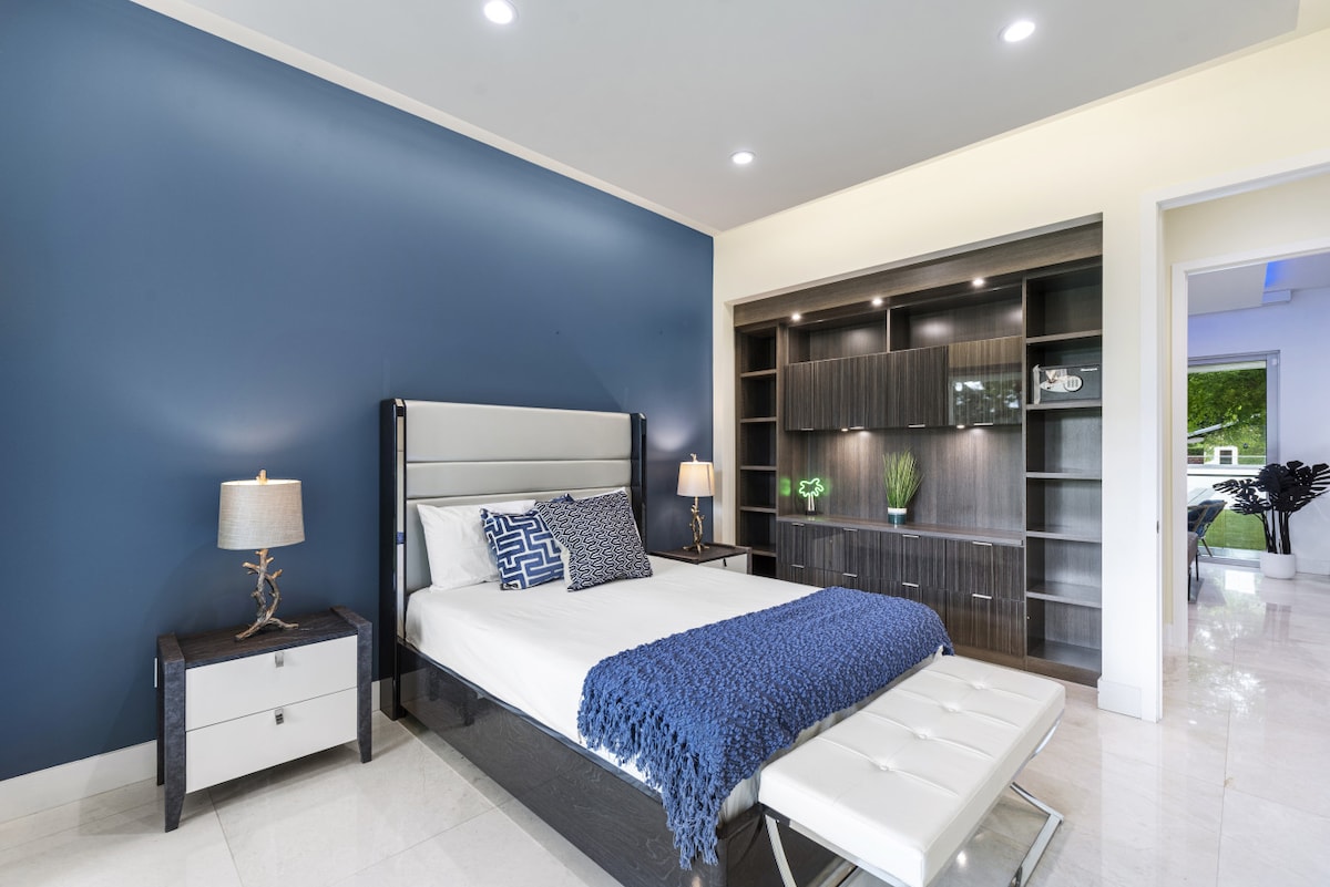 Amplio dormitorio con estanterías de diseño, banco de pared azul y mucha luz solar
