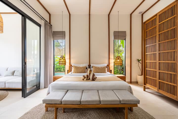 Stylish bedroom with large windows, natural light, and tropical views for a calming stay.