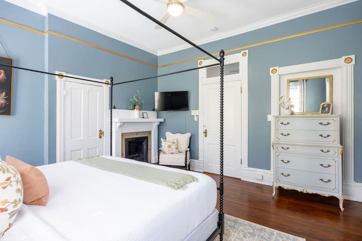 Elegant bedroom with sitting area,  TV,  fireplace (non-working), and antique charm