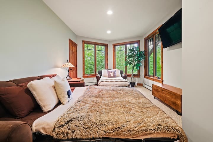 Chumba cha kulala chenye starehe kilicho na kitanda cha kifahari kilicho na matandiko laini, yaliyohamasishwa na manyoya, kitanda pacha cha kuvuta kwa ajili ya sehemu ya kulala ya ziada na madirisha makubwa yanayotoa mwonekano mzuri wa kijani kinachozunguka. Chumba hicho pia kina televisheni ya skrini bapa iliyowekwa ukutani kwa ajili ya entertai