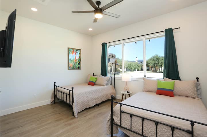 Уживајте во двојна удобност во оваа светла спална соба со два полни кревета и жив тропски декор.