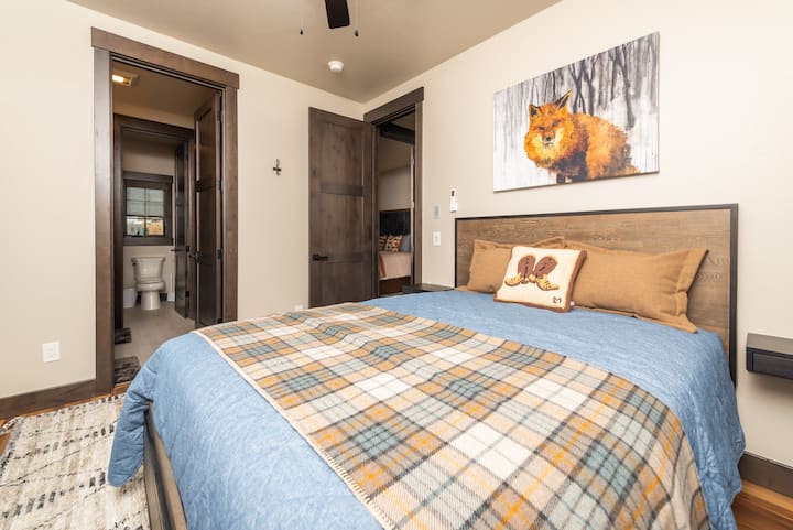 - Sleep soundly in this warm and inviting bedroom with rustic forest inspired accents
- Fox art and plaid bedding add charm and personality to your mountain stay
- Enjoy ensuite convenience with direct access to a private bathroom