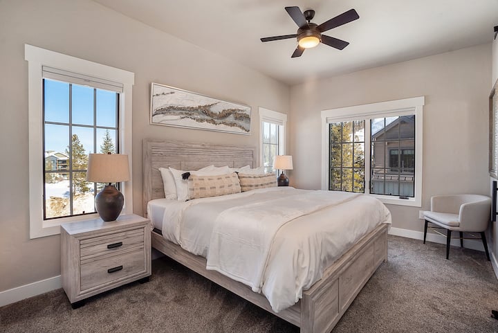- Inviting bedroom features soft textures, neutral tones, and wide windows framing peaceful alpine views
- King size bed, matching nightstands, and plush carpet complete the restful space
- Perfect for sleeping in or catching golden hour glow