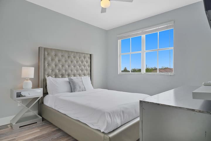 Ukiwa na kitanda aina ya plush queen, ubao wa kifahari wa kichwa na kinara chenye taa kando ya kitanda, acha chumba hiki cha kulala kikuondoe kwa ajili ya mapumziko yenye utulivu na utulivu.