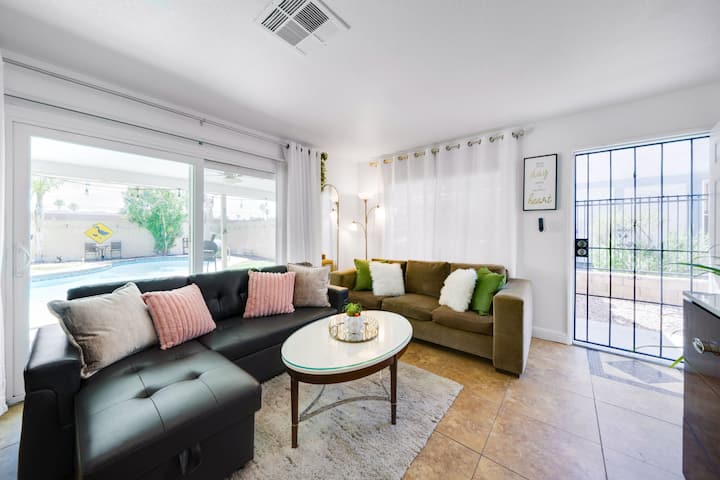 Светла дневна соба со поглед кон базен и удобно место за седење