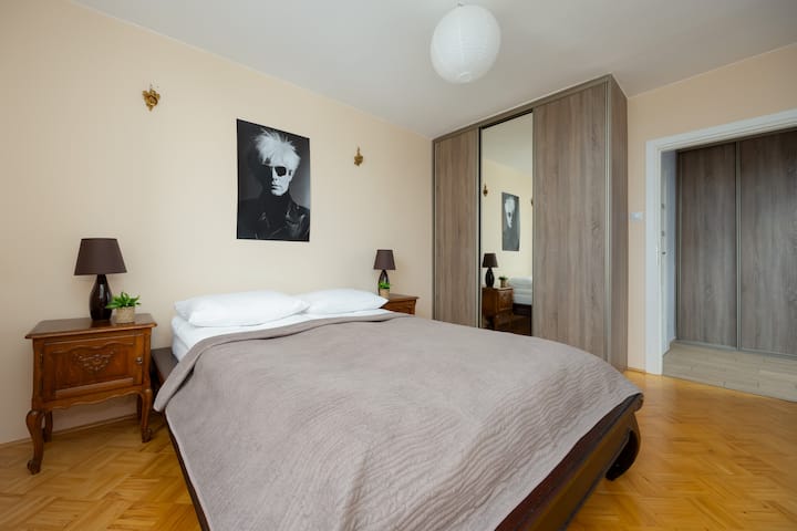 Een slaapkamer met een groot bed, schilderijen aan de muur en een kledingkast. Comfortabele en smaakvol ingerichte slaapruimte.