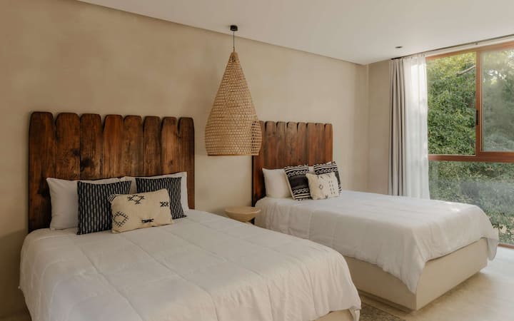 A bedroom with two queen beds, a slatted wood headboard, and crisp white bedding.