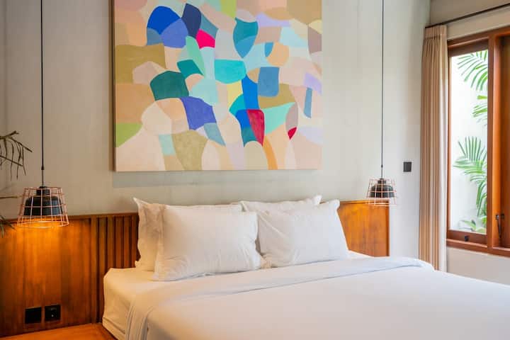 美丽的卧室，充满活力的艺术品和丰富的自然光线，提供完美的度假胜地