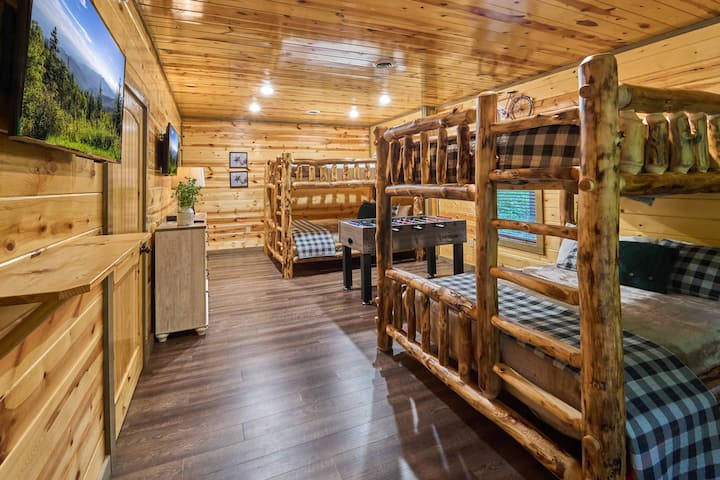 Esta espaciosa habitación con literas cuenta con dos literas de madera queen-over-queen, una mesa de futbolín y acceso a la terraza. Disfruta de un baño privado, un armario y un encanto rústico en una cabaña, perfecto para familias y grupos. ¡Un refugio acogedor y divertido para niños y adultos por igual!