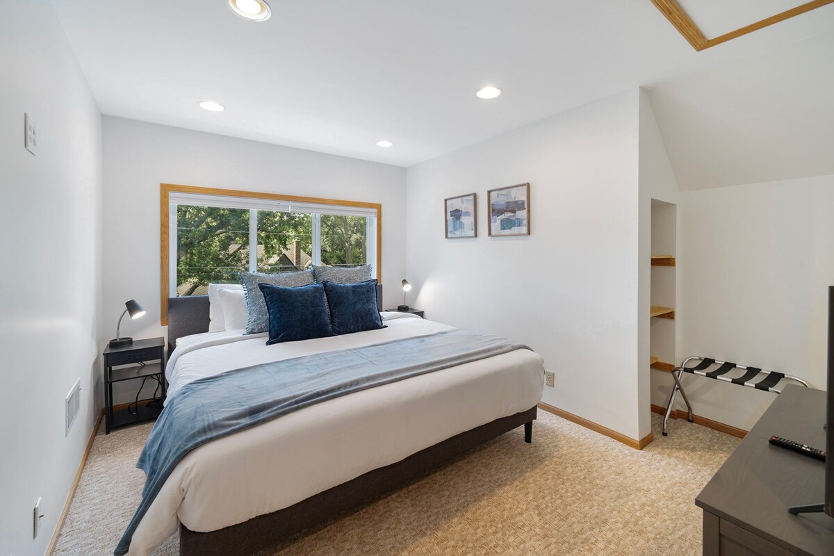 استمتع بالبياضات البيضاء الناعمة والوسائد البحرية الفاخرة في غرفة نومك الهادئة، حيث يتدفق الضوء الطبيعي عبر المناظر الخضراء.