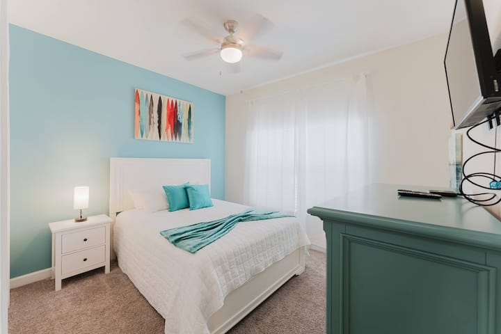 Oddýchnite si v tejto útulnej spálni zdobenej upokojujúcimi farbami a živými umeleckými dielami. Užite si mäkkú posteľnú bielizeň a sviežu modrú stenu, zatiaľ čo prirodzené svetlo prechádza cez priehľadné záclony a vytvára príjemnú a pokojnú atmosféru.