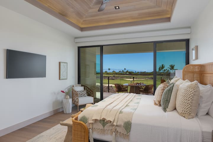Dormitorio 1 de la suite principal: este sereno dormitorio combina comodidad con impresionantes vistas, con grandes puertas corredizas que se abren al lanai con un exuberante paisaje de campo de golf.
