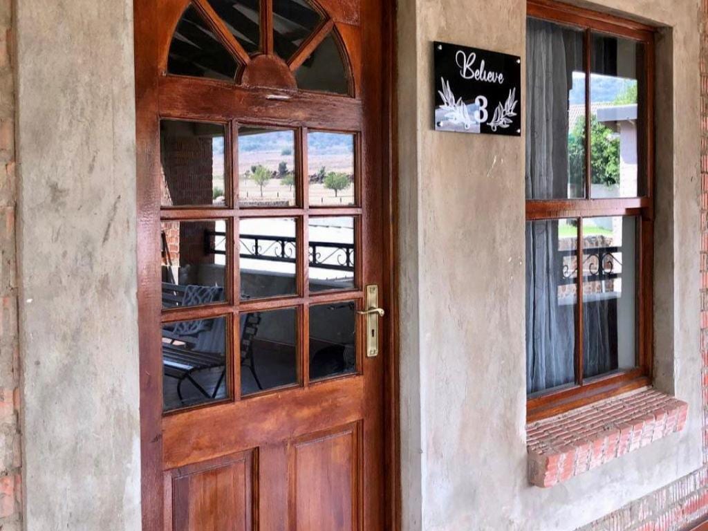 The entrance features a wooden door with a decorative glass panel, providing a view of the adjoining covered deck. The door frame is complemented by a rustic brick exterior and a small plaque displaying the number 3.