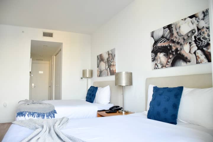 أسرّة مزدوجة مع فن زخرفي وإضاءة دافئة.