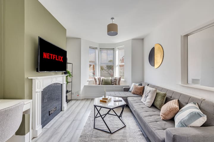 Un salon confortable avec un grand canapé d'angle, une Smart TV 50'' avec abonnement Virgin et Netflix inclus et un bureau, parfait pour ceux qui travaillent ou étudient à domicile.