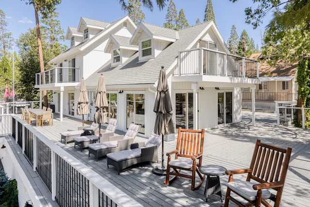 A spacious deck is featured, furnished with several loungers and wooden chairs, providing a comfortable area for relaxation. This outdoor space is bordered by trees, enhancing privacy, and showcases multiple patio umbrellas offering shade.