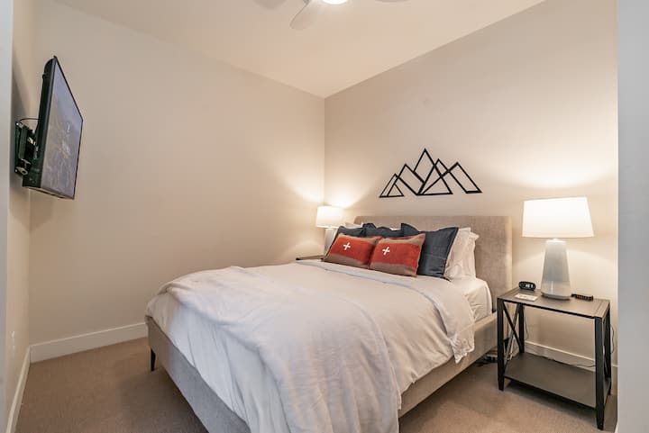 Este acogedor dormitorio con cama tamaño queen ofrece una televisión inteligente, ropa de cama lujosa e iluminación ambiental, perfecta para relajarse después de las aventuras en la montaña