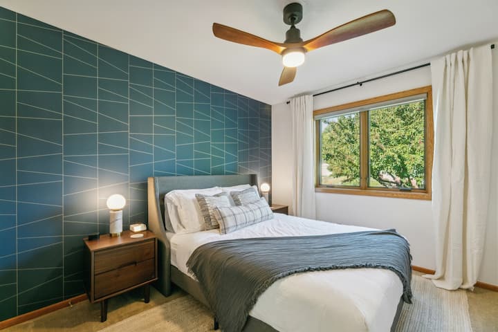 The Blue room features a features a queen-sized bed with a new luxury mattress, alarm clock with multiple charging ports, sound machine, and ceiling fan.