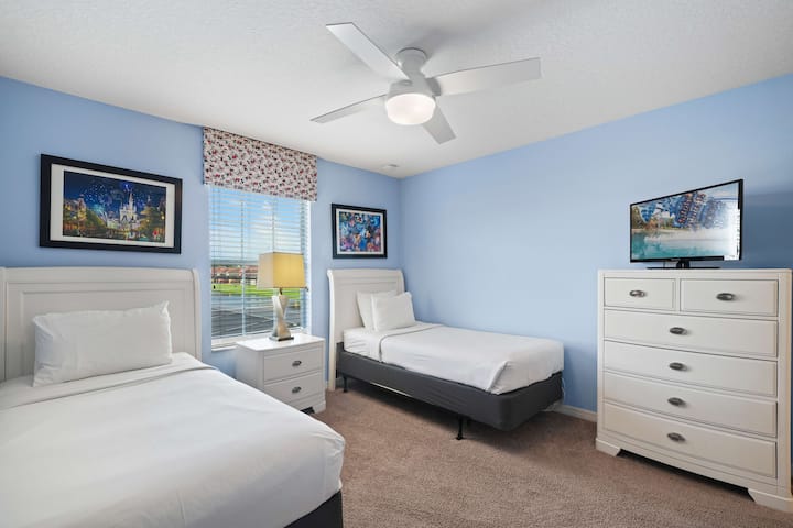 - Светла спална соба со двокреветни кревети, идеална за заеднички простор, украсена со светлосини ѕидови и уметнички дела на тема Дизни - вентилаторот на таванот и природната светлина создаваат свежо чувство - белиот гардеробер и телевизорот обезбедуваат складирање и забава за функционална поставеност