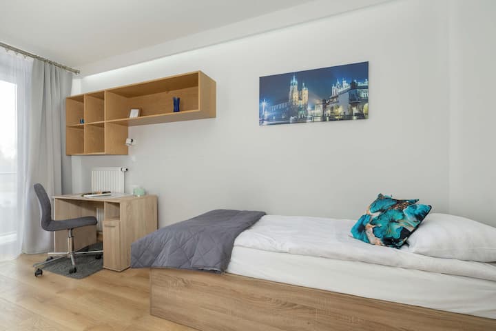 Საძინებელი კომფორტული ერთადგილიანი საწოლითა და სამუშაო მაგიდით სკამით.