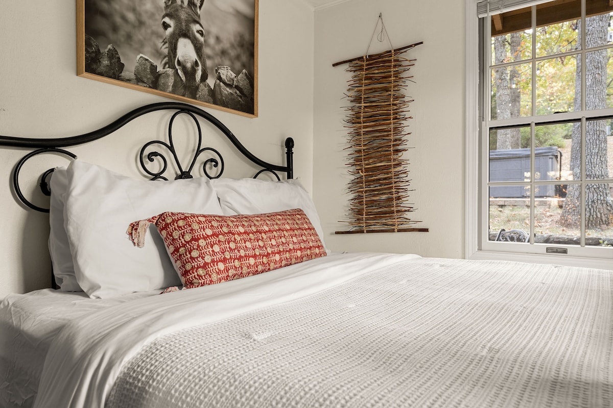 - Спете спокойно в тази приветлива спалня с винтидж ковано желязно легло
- Изкуството на стените, вдъхновено от природата, и тъканите акценти добавят топлина и текстура
- Събудете се с изглед към гората и хидромасажната вана точно пред прозореца си