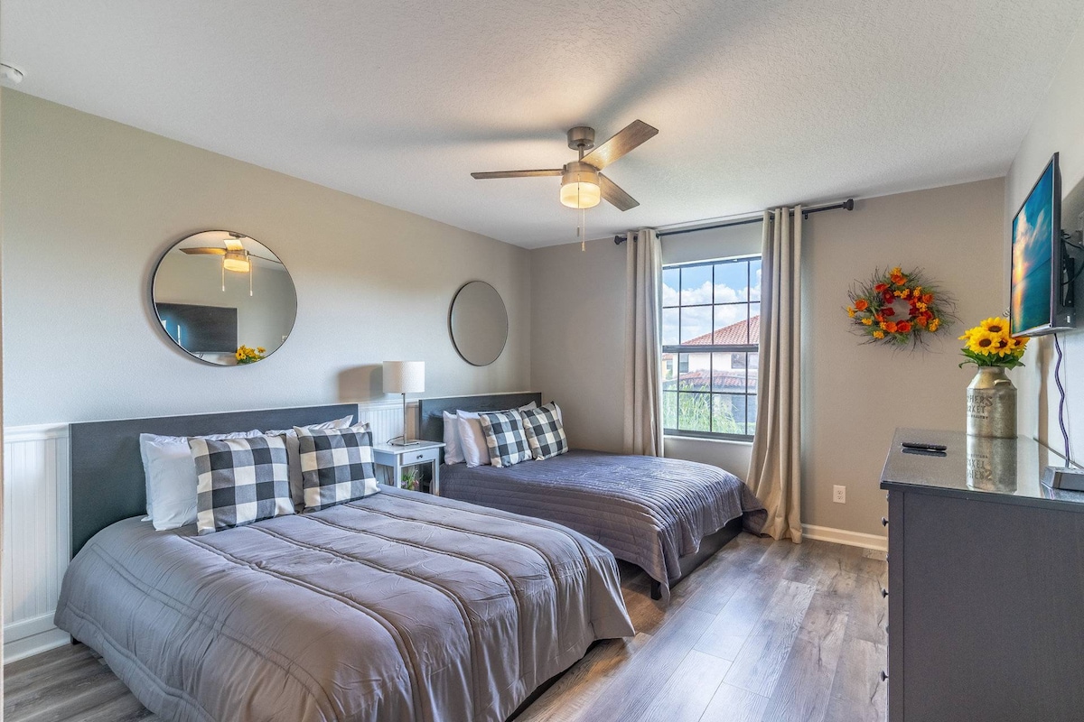 חדר שינה בקומה השנייה עם 2 מיטות מלאות וטלוויזיה תלוית קיר