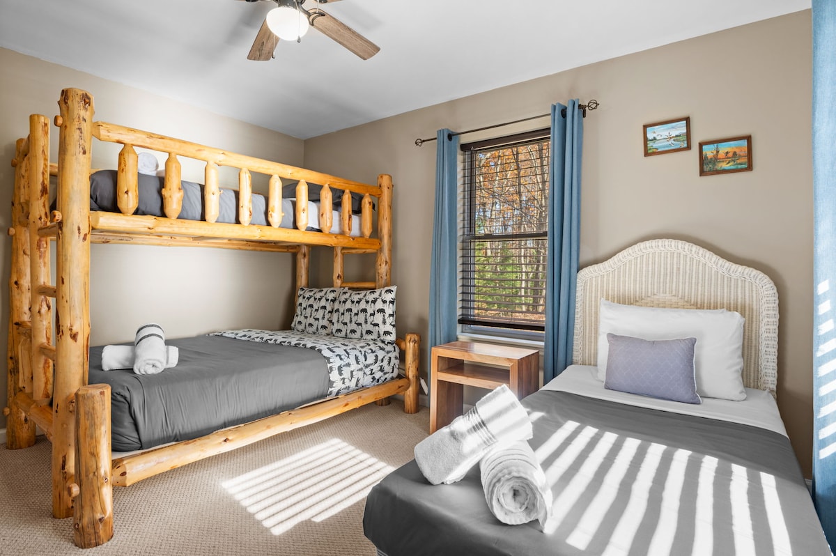 Grandi finestre riempiono la stanza di luce naturale, mettendo in risalto la palette di colori tenui e i caldi dettagli in legno.