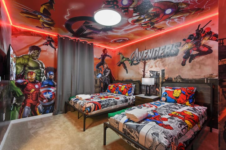 Chumba cha kulala chenye mandhari ya Avengers kilicho na vitanda viwili, michoro ya ukutani na mapambo mahiri.