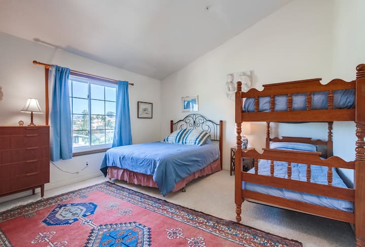 Спалня 3 Просторна стая с двойно легло, дървени двуетажни легла и цветен декор с изглед към големия прозорец