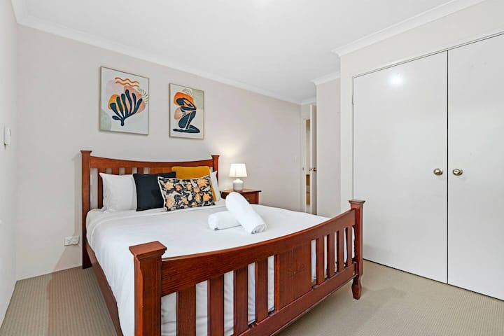 ผ่อนคลายในห้องพักที่อบอุ่นด้วยเตียงคู่ที่สะดวกสบาย (โครงไม้สีเข้มผ้าปูที่นอนสีขาว)