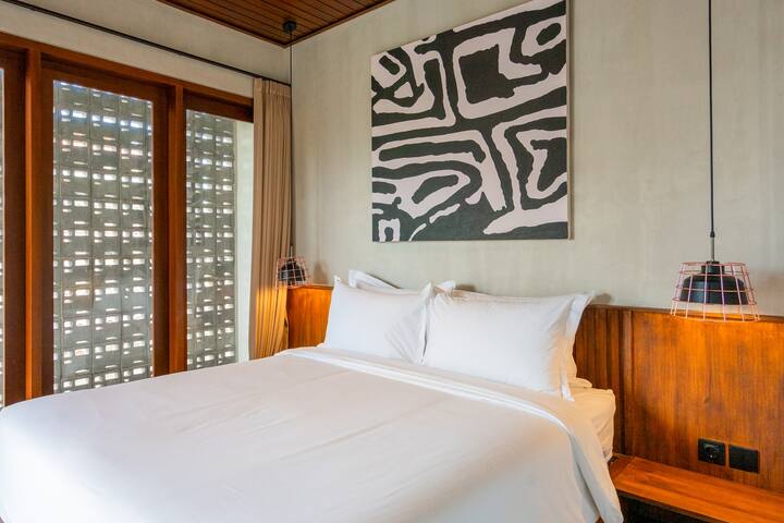 Dhomë gjumi elegante me vepra arti moderne dhe dritë natyrale për një pushim të qetë