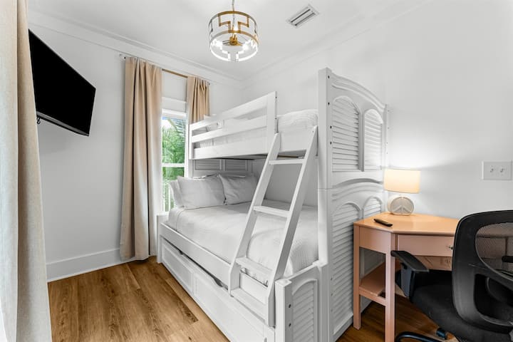 Este dormitorio cuenta con una litera inferior de tamaño completo, una litera superior doble y una cama nido extraíble doble. El dormitorio también cuenta con un escritorio, un televisor inteligente y una puerta que conduce al balcón del segundo piso, que ofrece vistas al patio trasero y p
