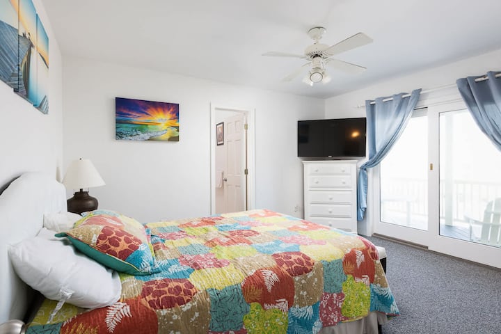 Quarto principal Queen de nível médio com banheiro privativo completo, acesso ao deck e TV
