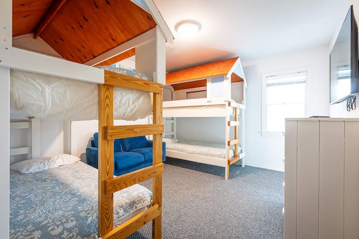 Quarto principal de nível médio com dois beliches e sofá com banheiro completo e TV