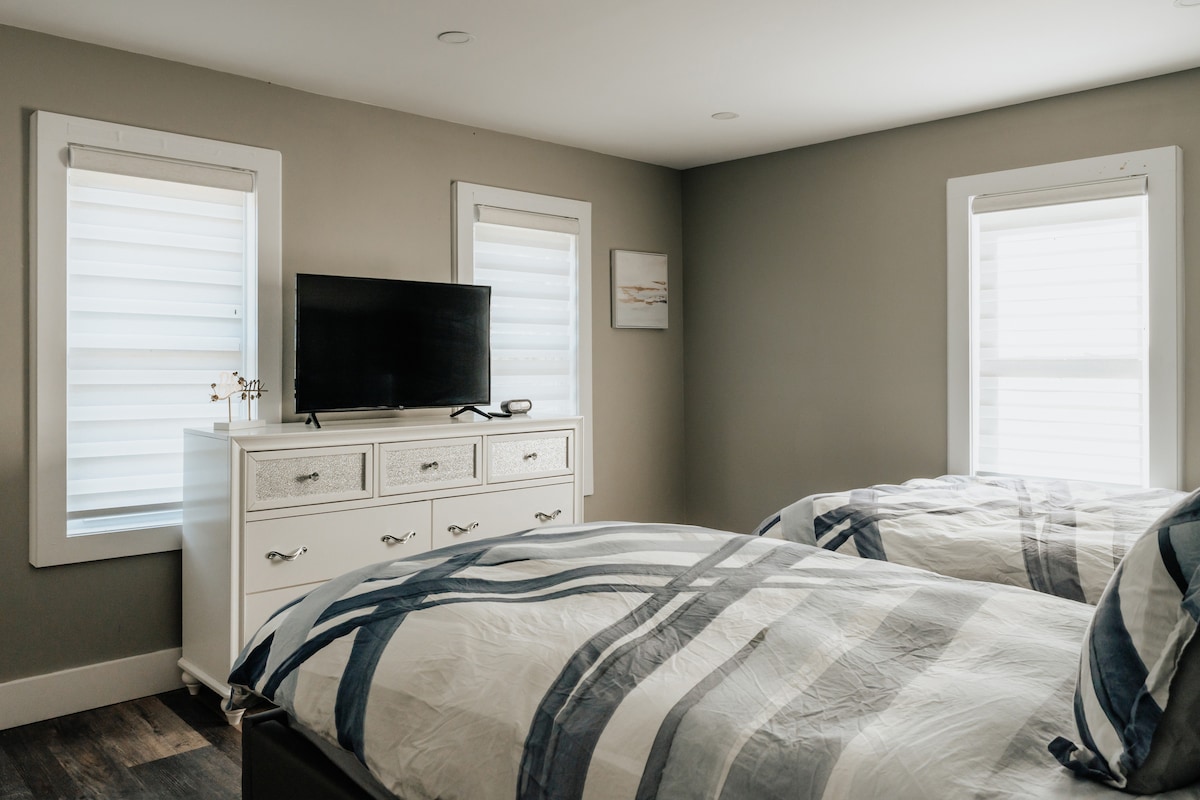 Un amplio dormitorio amueblado con dos camas dobles y TV, que proporciona un espacio cómodo y relajante para varios huéspedes.